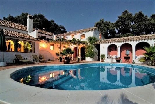A stunning, ageless society with a grand house and illuminated pool under the night sky.